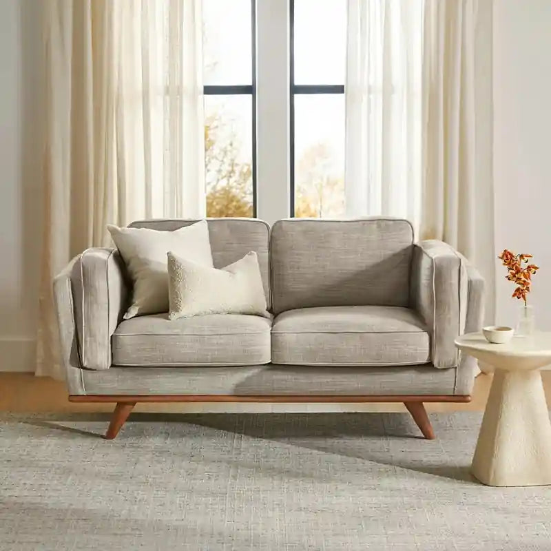 The neutral upholstered settee complements various interiors, functioning equally as a stylish couch set