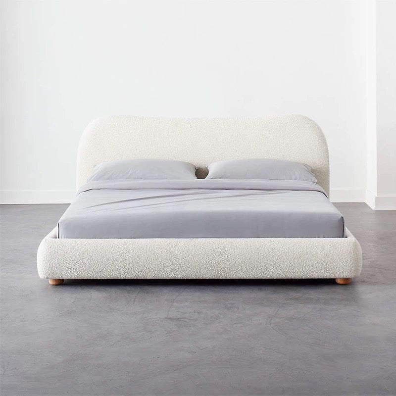 The soft off-white bouclé fabric, curved padded headboard, and neatly rounded base offer a minimalist appeal