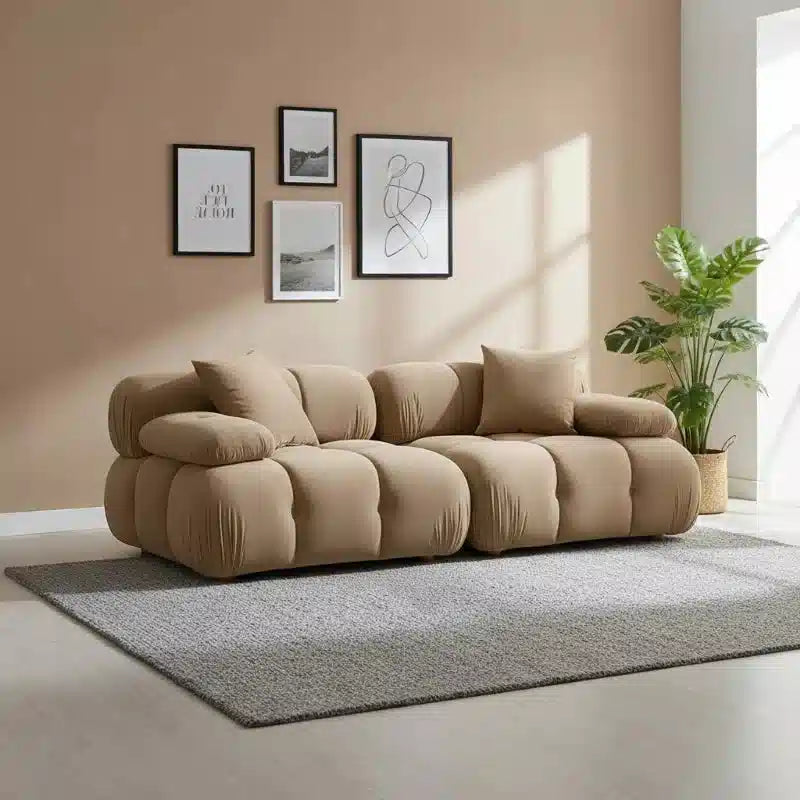 Beige sofa in a living room with framed art on the wall and a plant.