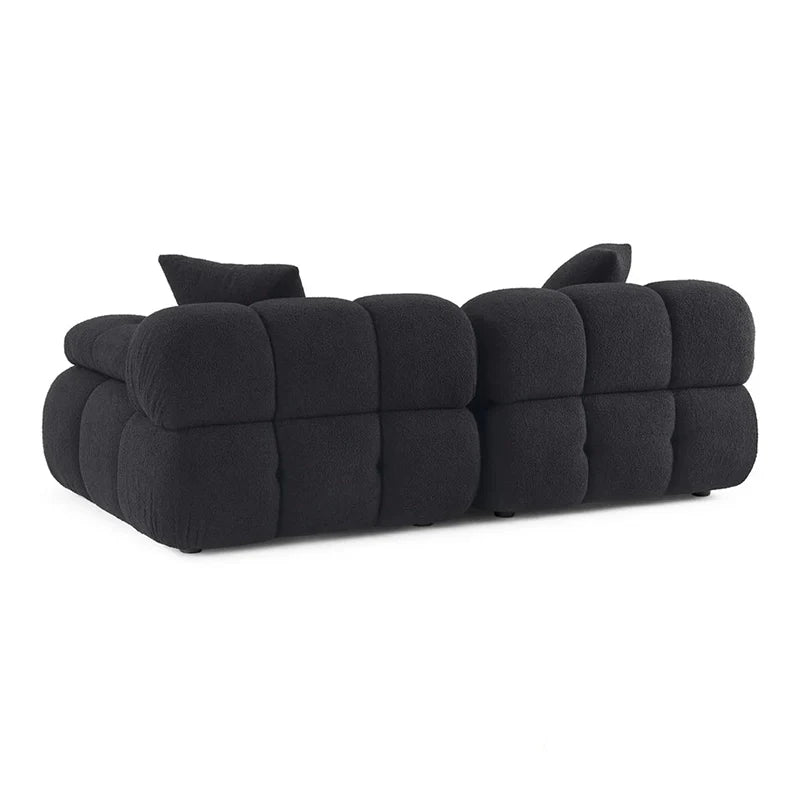 This contemporary sofa design features deeply tufted cushions, pillow-like armrests, and soft rounded edges that define both comfort and style. 