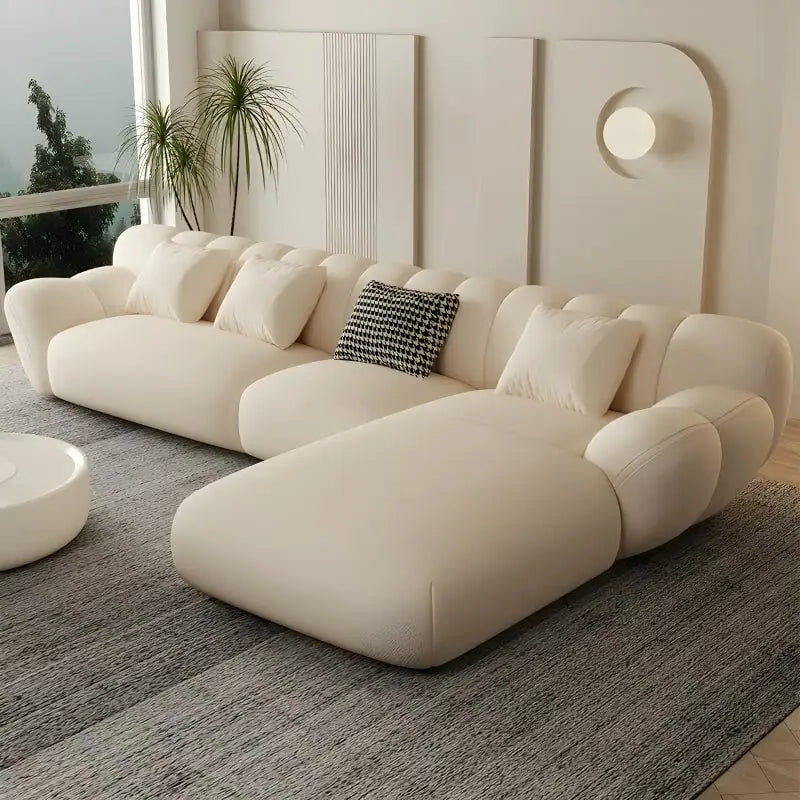 Modern living room with a large beige sectional sofa, decorative pillows, and a coffee table.