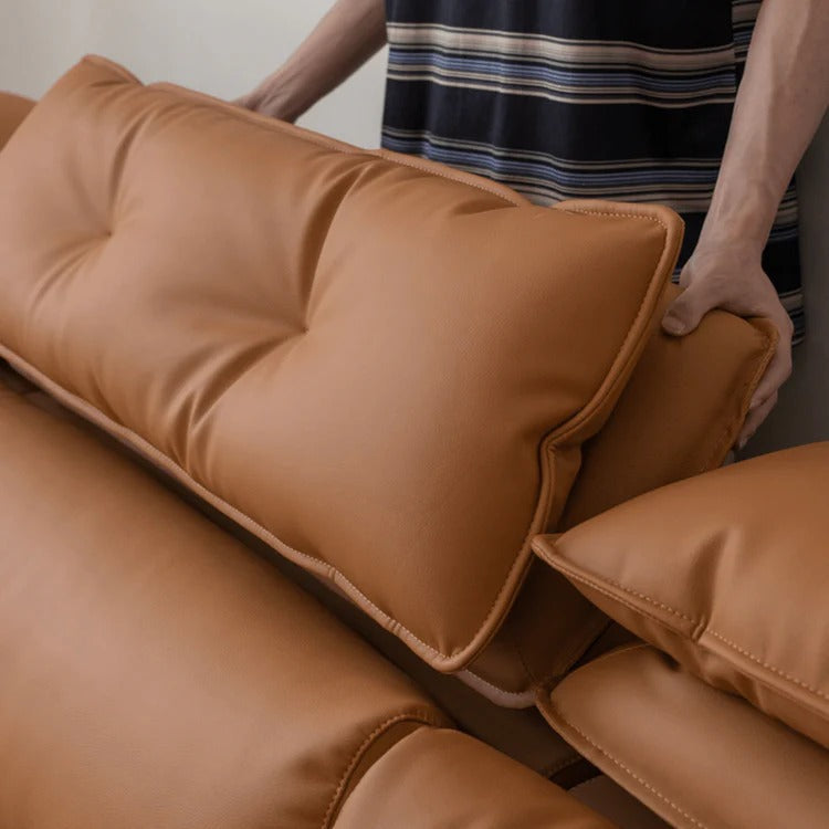 Person adjusting brown cushions on a sofa
